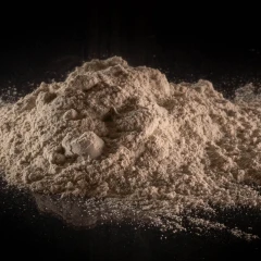 T-5 Calcium Bentonite Clay, heap of light tan powder on a dark background – view 2