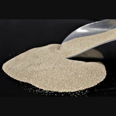 ZeoClear L fine attapulgite, fine light tan granules poured from a scoop on a dark background